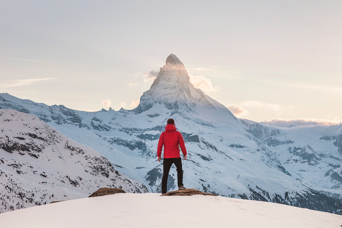 A person looking toward a mountain peak, ready for the journey ahead